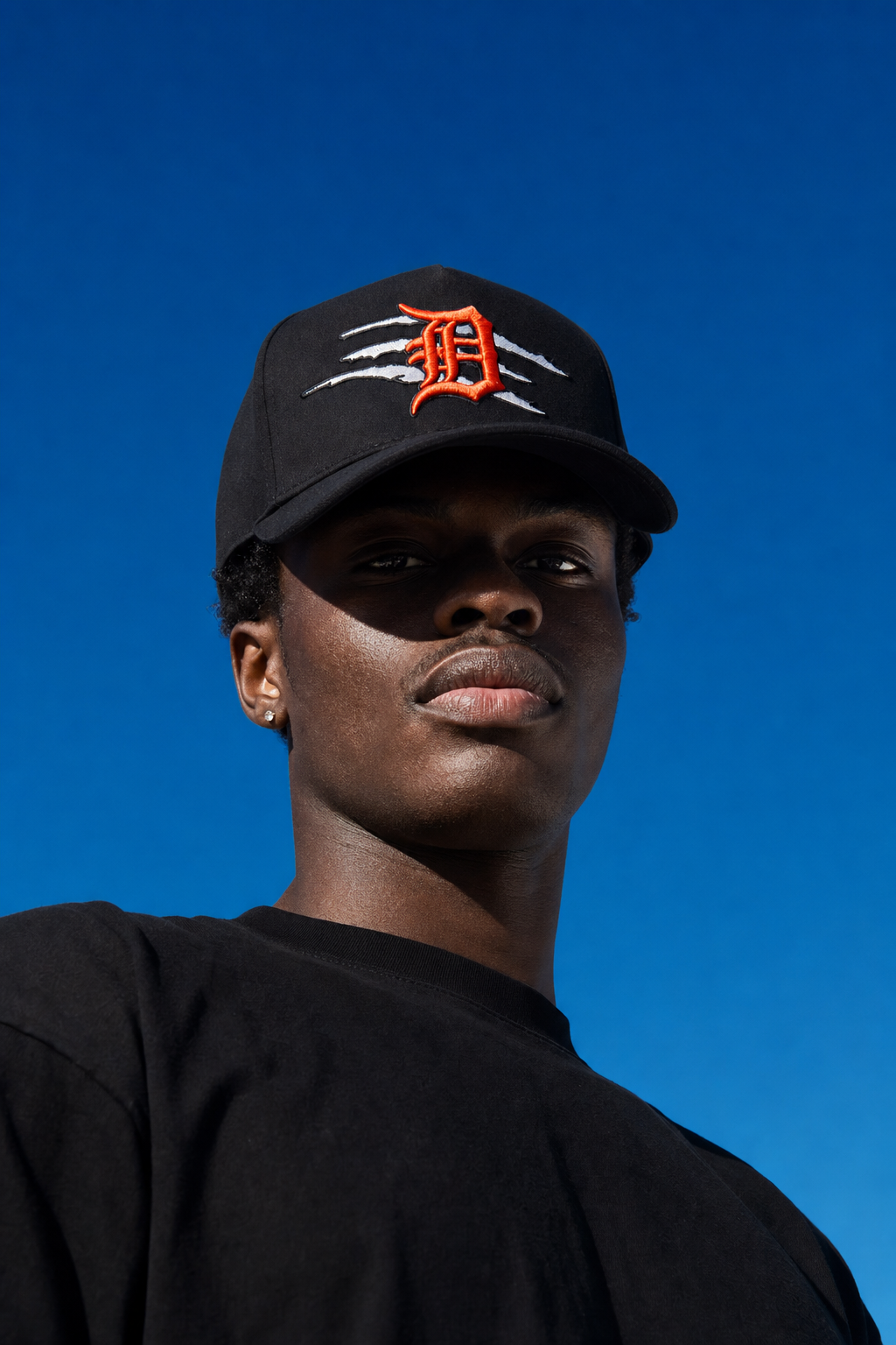 Low-angle shot of a model in a MADHOURS snapback against open sky